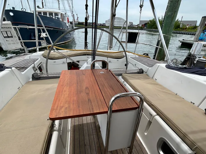 Blue Moon Yacht Photos Pics Cockpit of 2003 Beneteau First 47.7 sailboat with wooden table and cushioned seating.