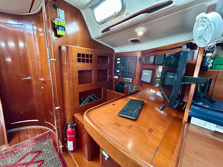 Blue Moon Yacht Photos Pics Navigation station inside 2003 Beneteau First 47.7 sailboat, featuring wood finish and control panels.