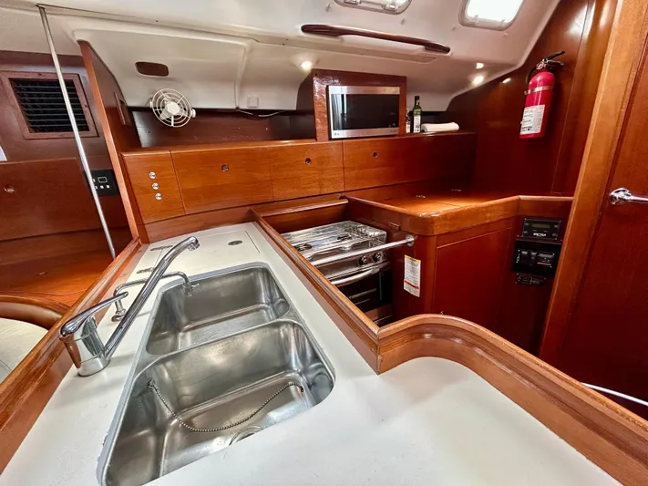 Blue Moon Yacht Photos Pics Beneteau First 47.7 2003 yacht kitchen with wooden cabinetry, stainless steel sink, and modern appliances.
