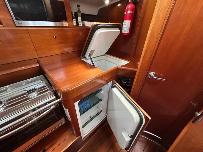Blue Moon Yacht Photos Pics 2003 Beneteau First 47.7 yacht kitchen with open fridge and wooden cabinetry.