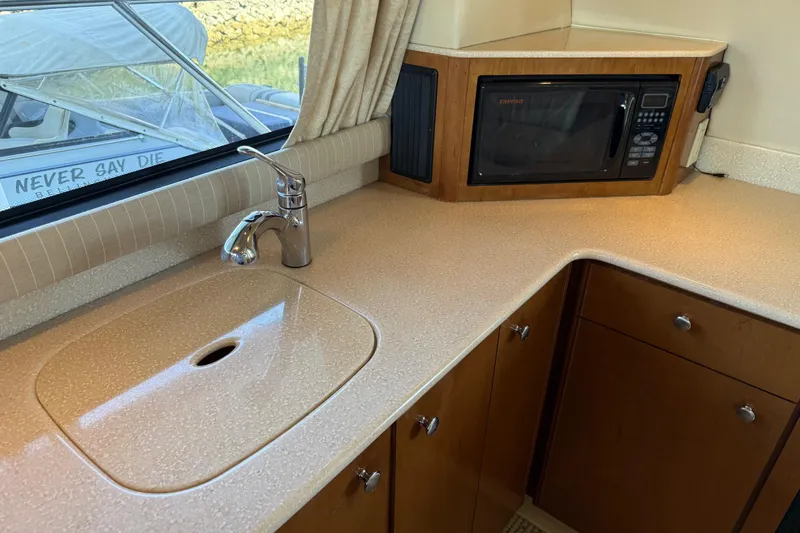  Yacht Photos Pics 2005 Meridian 341 Sedan kitchen with sink, microwave, and wooden cabinetry.