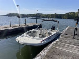A 2021 Tahoe 1950 boat docked on a serene lake with wooded shoreline.