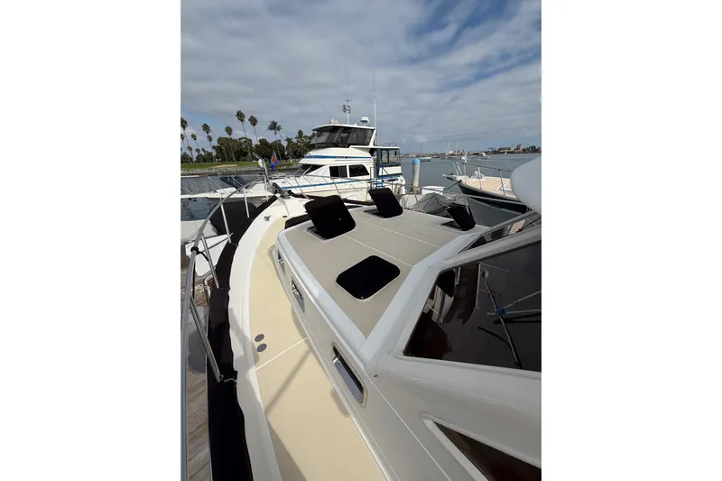 Queenie Yacht Photos Pics 1988 Offshore Yachts 48 Sedan docked, featuring spacious deck and sleek design under cloudy sky.