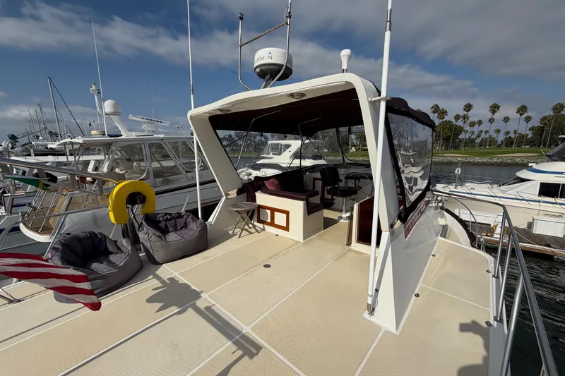Queenie Yacht Photos Pics 1988 Offshore Yachts 48 Sedan docked, featuring spacious deck and seating area under clear skies.
