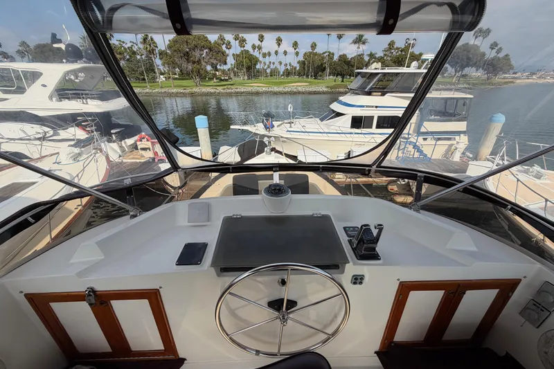 Queenie Yacht Photos Pics Cockpit view of 1988 Offshore Yachts 48 Sedan, docked with scenic marina backdrop.