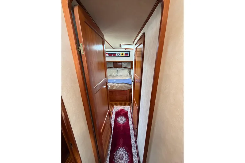Queenie Yacht Photos Pics Interior hallway of 1988 Offshore Yachts 48 Sedan, featuring wood doors and cozy bedroom.