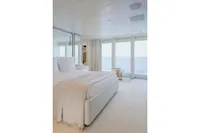 Luxurious yacht bedroom with ocean view, featuring elegant white decor and large windows.