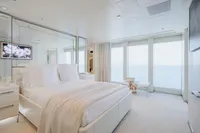 Luxurious yacht bedroom with ocean view, featuring elegant white decor and modern design.