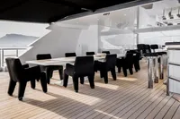 Luxurious yacht deck with elegant dining area, featuring black chairs and a sleek table.