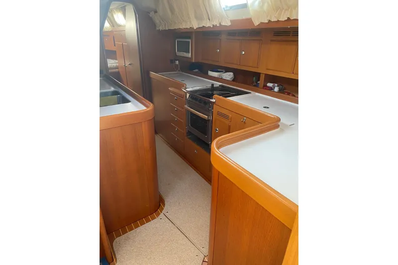  Yacht Photos Pics Luxurious 2007 Hallberg-Rassy 54 yacht interior kitchen with wooden cabinetry and modern appliances.