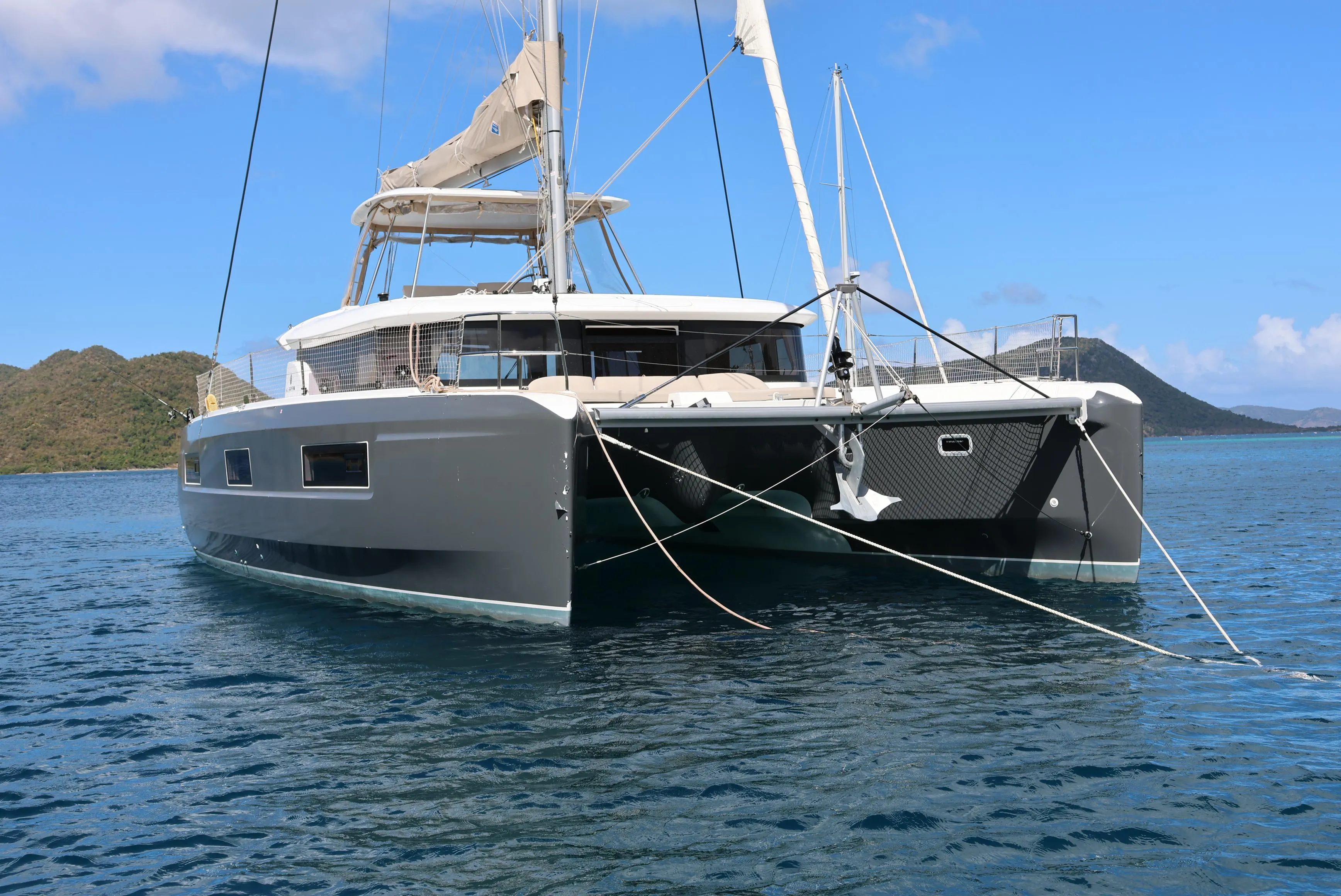 2022 Lagoon 46 catamaran anchored in serene blue waters with scenic island backdrop.