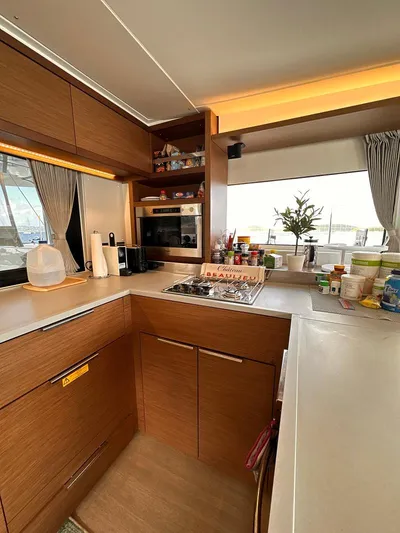  Yacht Photos Pics Modern kitchen interior of 2022 Lagoon 46 yacht with wooden cabinetry and appliances.