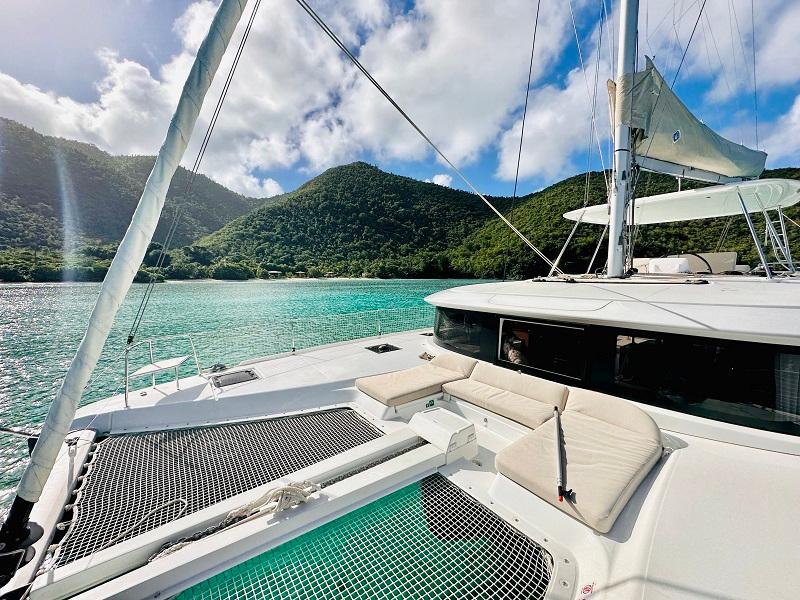 Lagoon 46 catamaran (2022) anchored in turquoise waters with lush green hills.