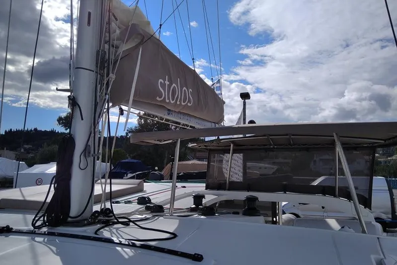 Stolos Yacht Photos Pics 2020 Lagoon 42 catamaran with sails, docked under a partly cloudy sky.
