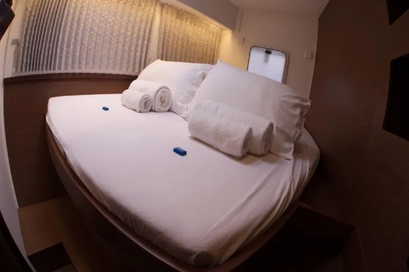 Stolos Yacht Photos Pics Cozy cabin interior of 2020 Lagoon 42 yacht with neatly arranged bed and towels.