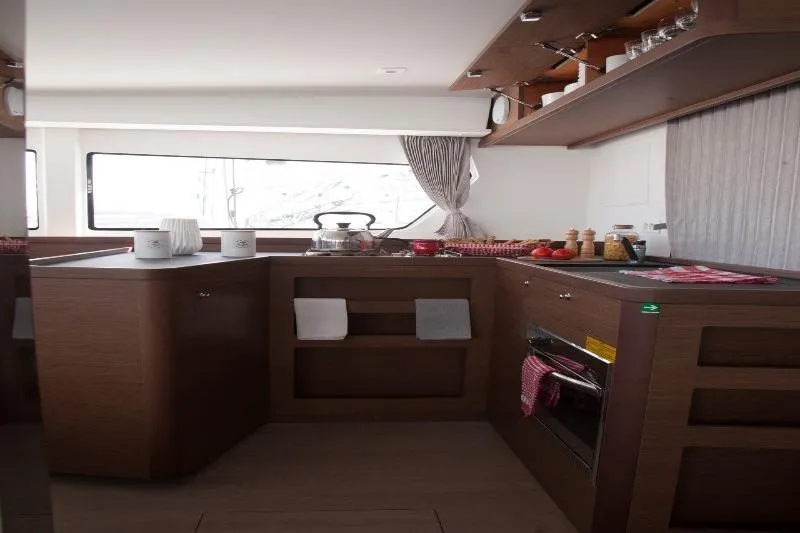 Stolos Yacht Photos Pics Modern kitchen interior of 2020 Lagoon 42 catamaran, featuring wood cabinetry and sleek design.