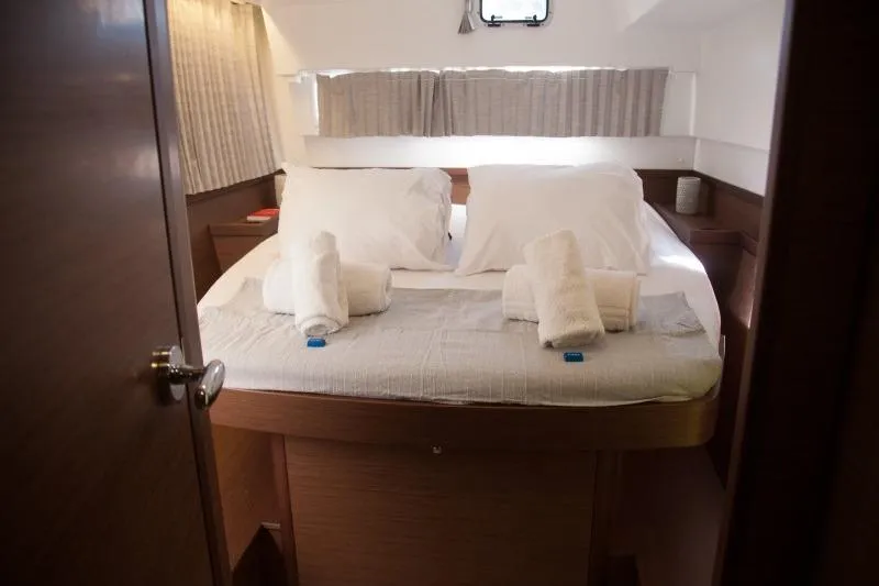 Stolos Yacht Photos Pics Cozy cabin interior of 2020 Lagoon 42 yacht with neatly arranged bed and towels.