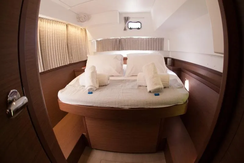 Stolos Yacht Photos Pics Luxurious cabin interior of 2020 Lagoon 42 catamaran with cozy bed and elegant decor.