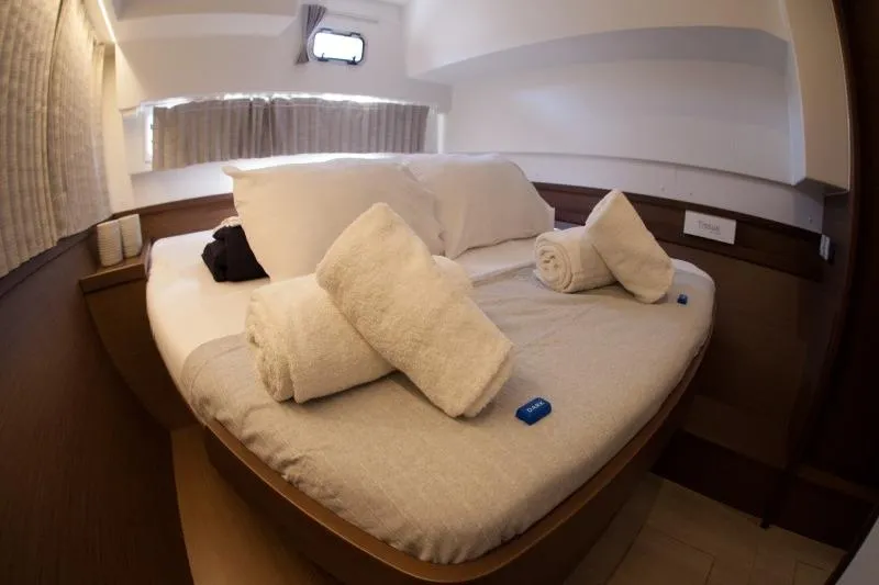 Stolos Yacht Photos Pics Cozy cabin interior of 2020 Lagoon 42 yacht with neatly arranged bed and towels.