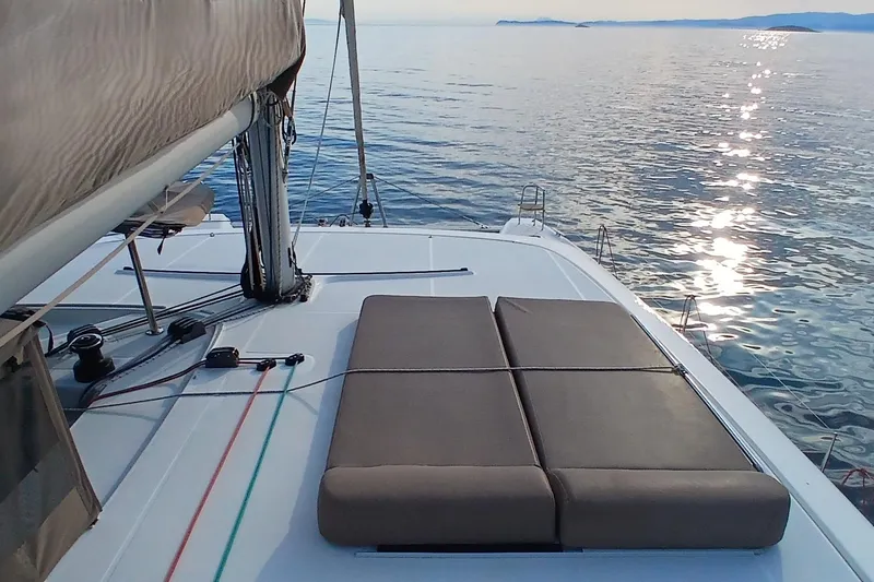 Stolos Yacht Photos Pics 2020 Lagoon 42 catamaran deck with sunbed, calm sea, and distant islands.