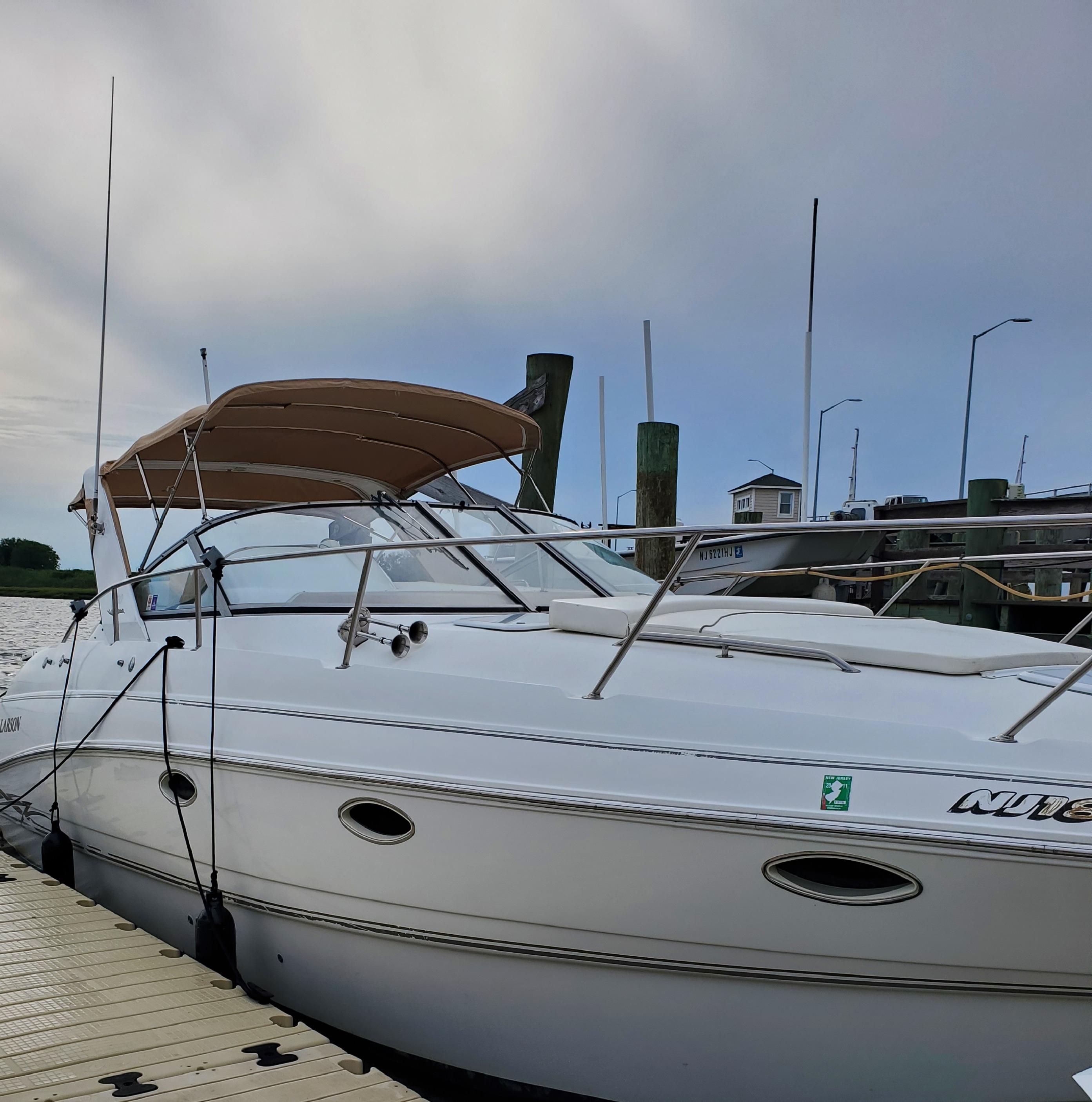 2000 Larson 330 CABRIO boat docked at marina under cloudy sky.