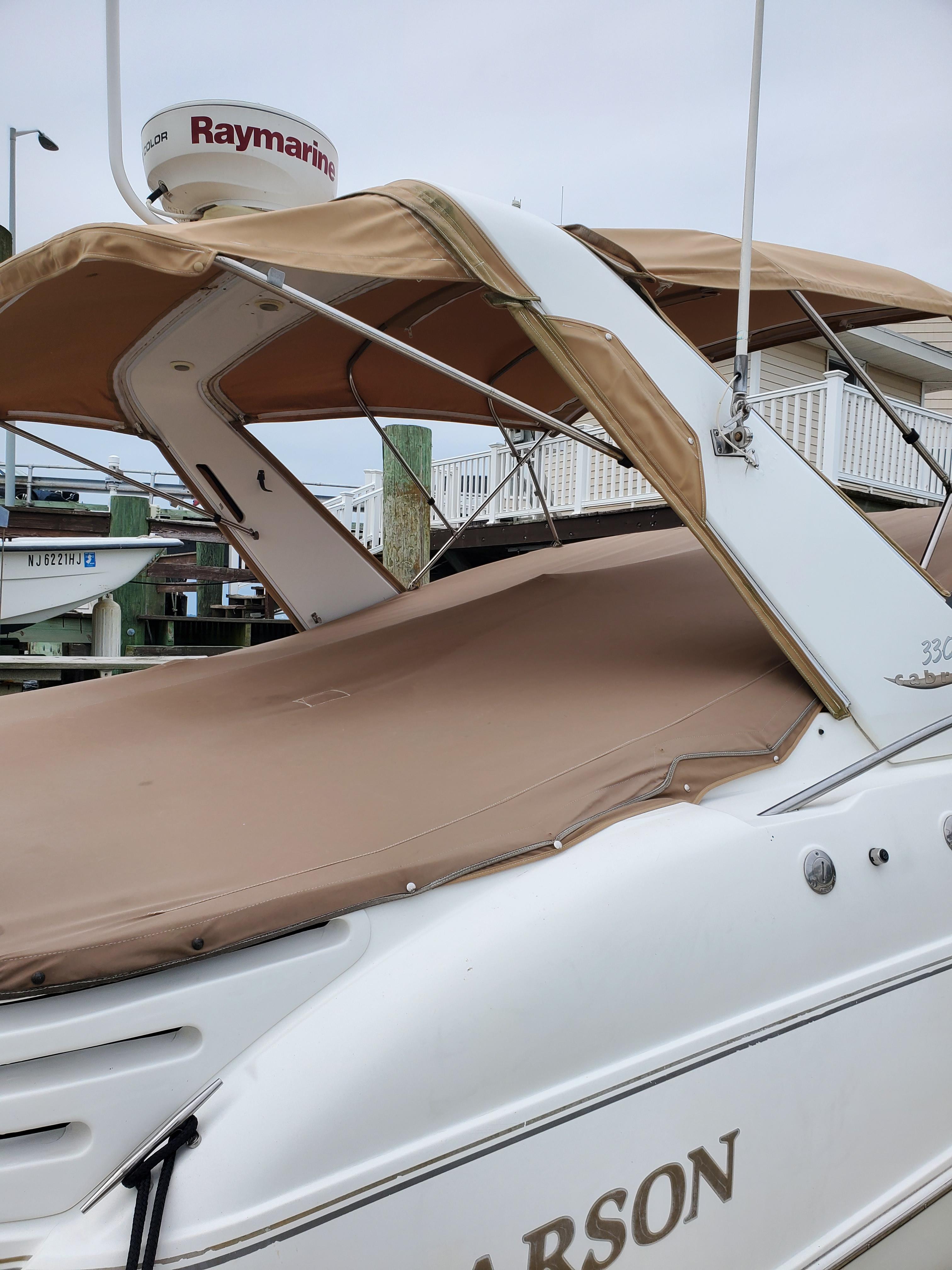 2000 Larson 330 CABRIO boat with tan canopy and Raymarine radar at dock.