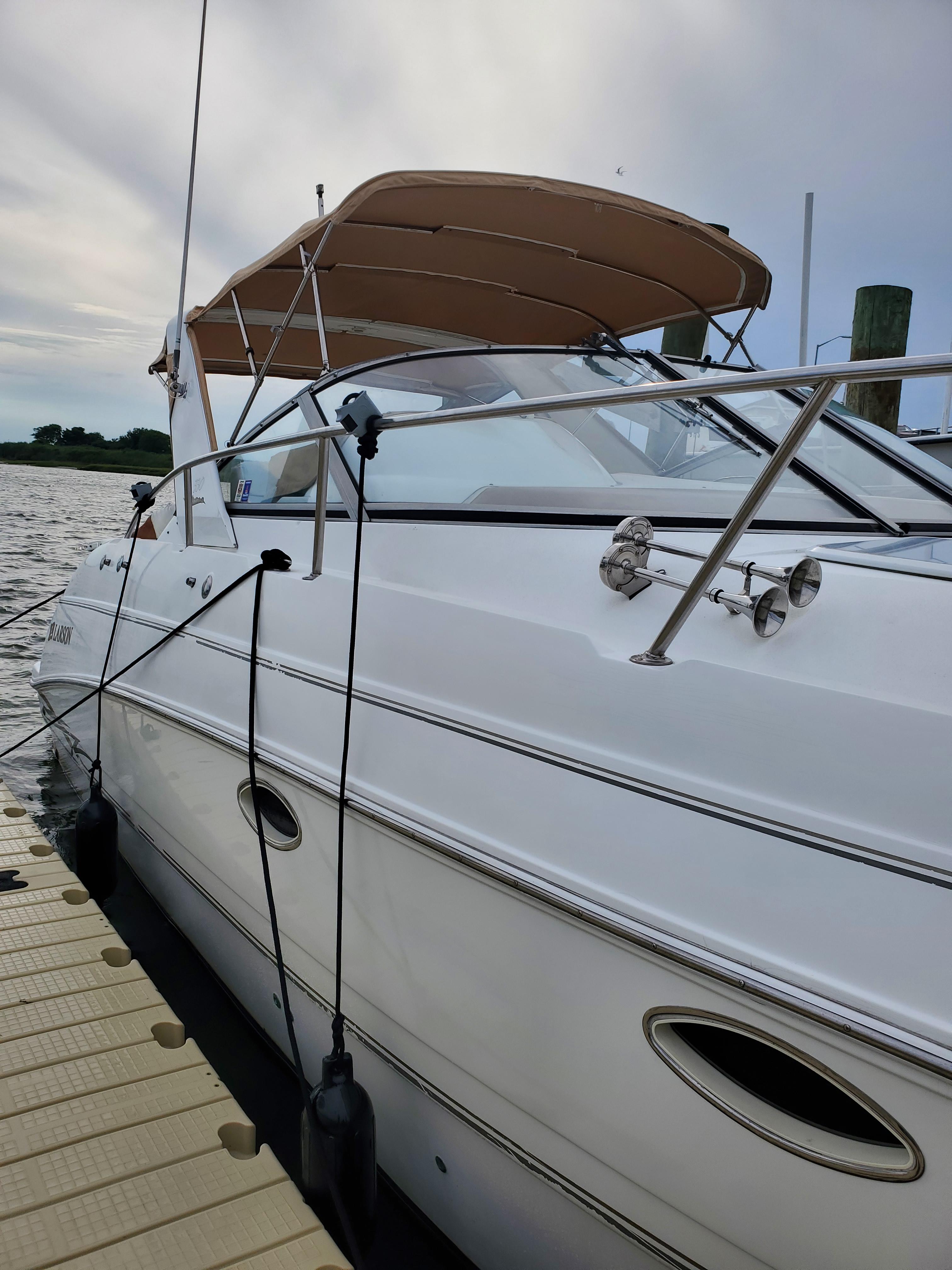 2000 Larson 330 Cabrio boat docked, featuring sleek design and canopy.