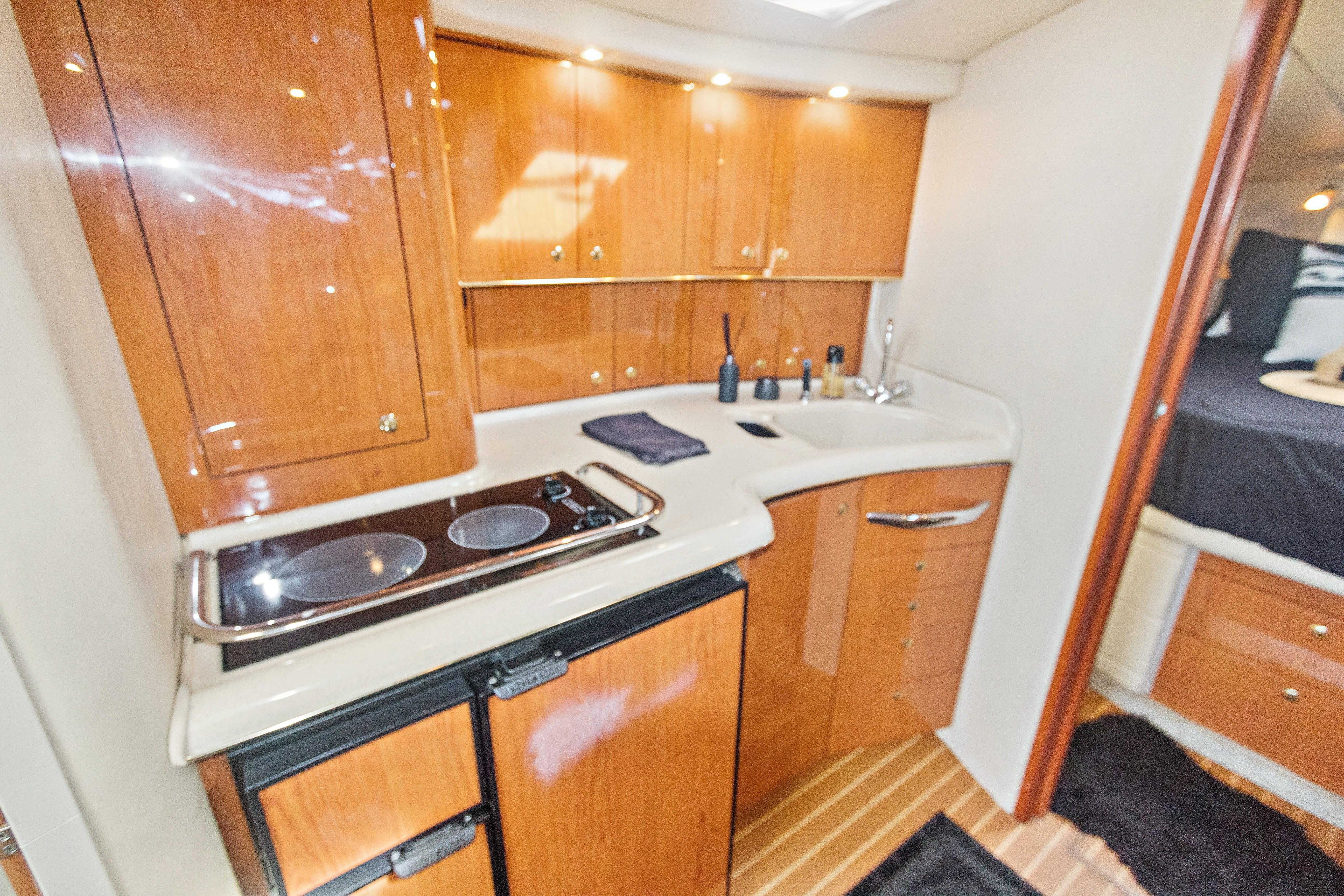 2000 Sea Ray 370 Express Cruiser interior kitchen with wooden cabinets and modern appliances.