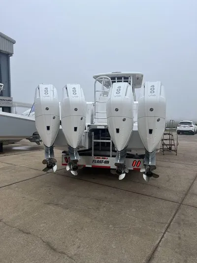  Yacht Photos Pics 2024 Twin Vee 400 GFX boat with four powerful outboard engines, docked on a concrete surface.