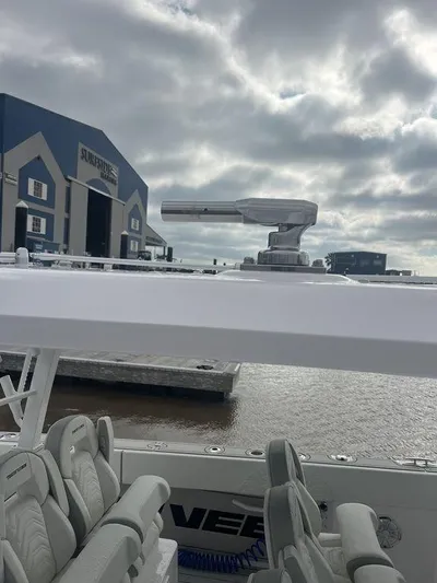  Yacht Photos Pics 2024 Twin Vee 400 GFX boat with sleek design, docked near a marina under cloudy skies.