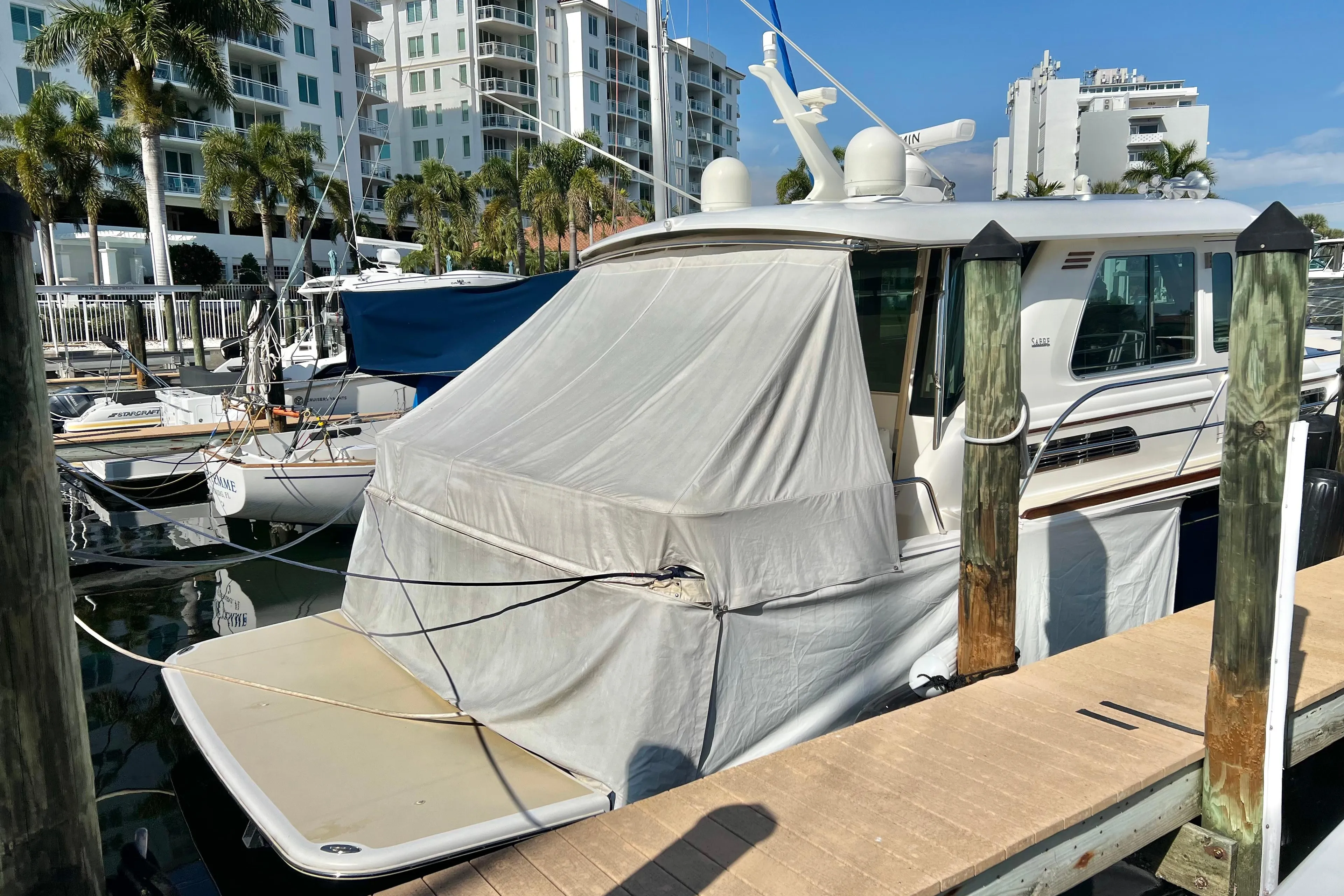 2017 Sabre 48 Salon Express yacht docked at marina with cover, surrounded by buildings.