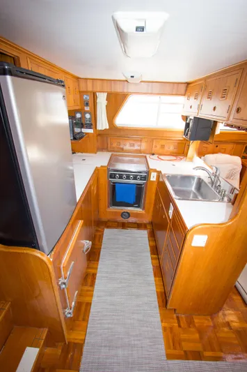 Seascape Yacht Photos Pics 1989 Cheoy Lee 53 yacht kitchen with wood cabinetry, stainless steel appliances, and compact design.