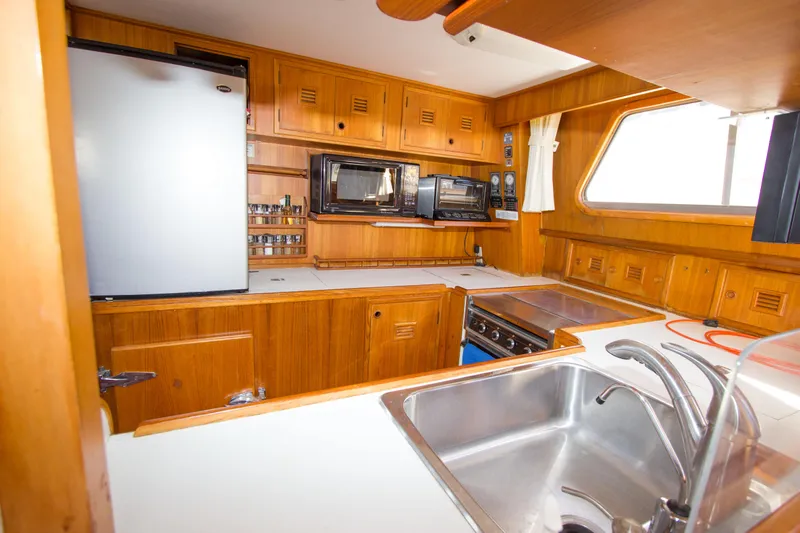 Seascape Yacht Photos Pics 1989 Cheoy Lee 53 yacht kitchen with wooden cabinetry, stainless steel sink, and modern appliances.