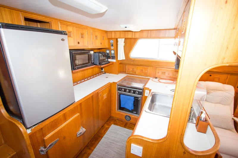 Seascape Yacht Photos Pics 1989 Cheoy Lee 53 yacht kitchen with wood cabinetry, appliances, and a cozy layout.
