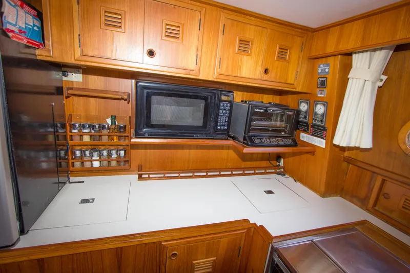 Seascape Yacht Photos Pics Galley kitchen in 1989 Cheoy Lee 53 yacht with wood cabinetry and modern appliances.