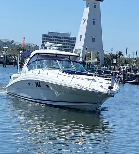  Yacht Photos Pics 2006 Sea Ray 44 Sundancer yacht cruising near a lighthouse in a marina.