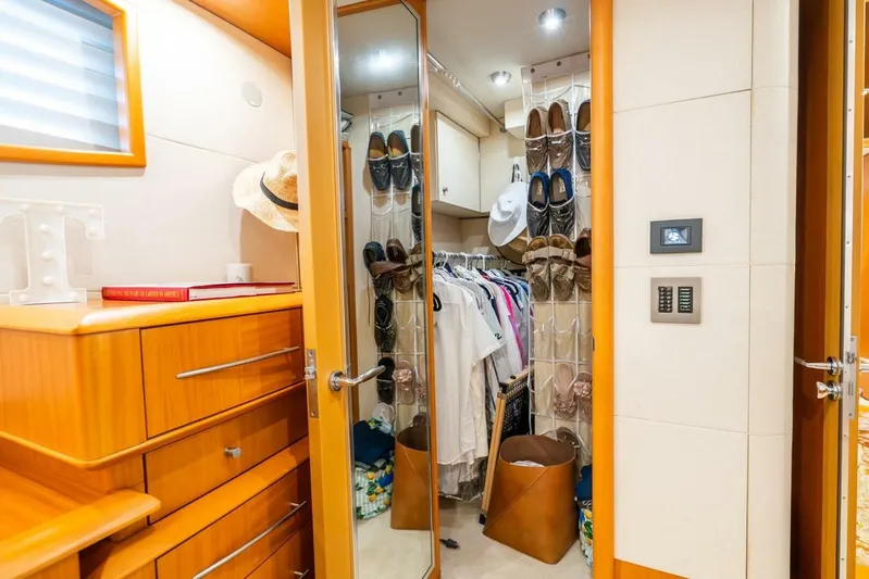 Serenity Yacht Photos Pics Luxurious 2008 Lazzara motor yacht closet with clothes, shoes, and wooden cabinetry.