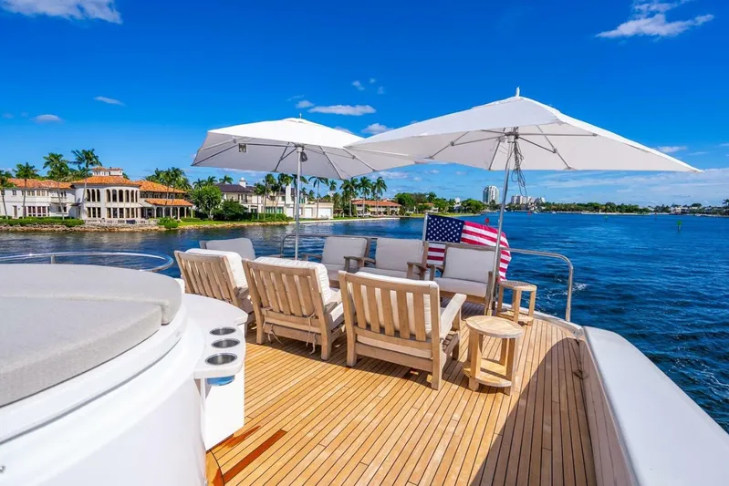 Serenity Yacht Photos Pics Luxurious 2008 Lazzara motor yacht deck with seating, umbrellas, and American flag, overlooking waterfront homes.