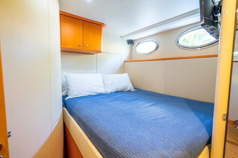 Serenity Yacht Photos Pics Cozy bedroom in 2008 Lazzara motor yacht with blue bedding and porthole windows.