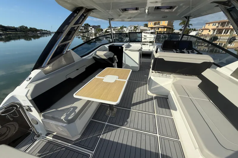  Yacht Photos Pics Aquila 32 Sport 2021 boat interior with seating and table, docked in a serene marina.