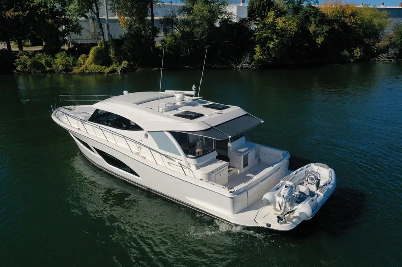  Yacht Photos Pics 2025 Riviera 465 SUV yacht cruising on a serene river.