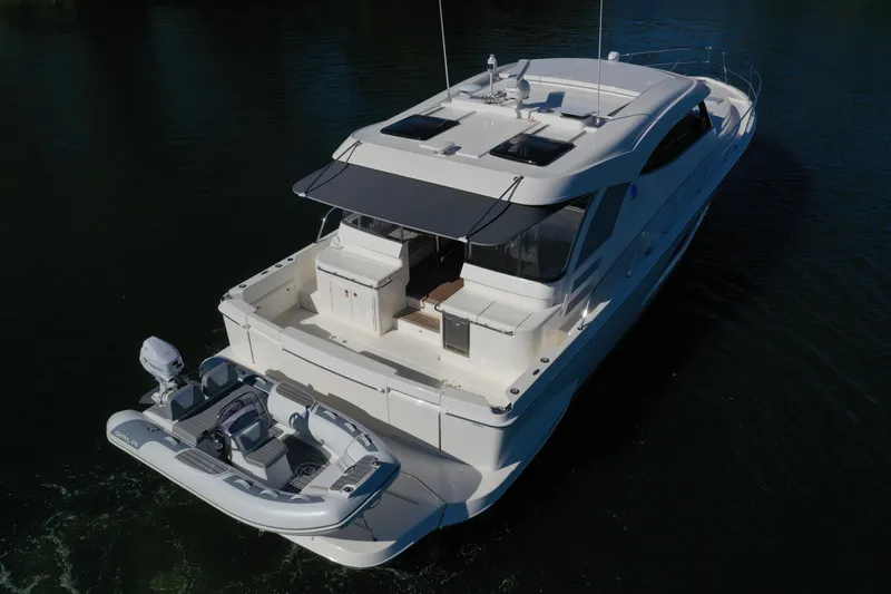  Yacht Photos Pics 2025 Riviera 465 SUV yacht with tender on water, rear view.