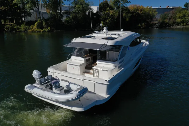  Yacht Photos Pics 2025 Riviera 465 SUV yacht cruising on a serene river.