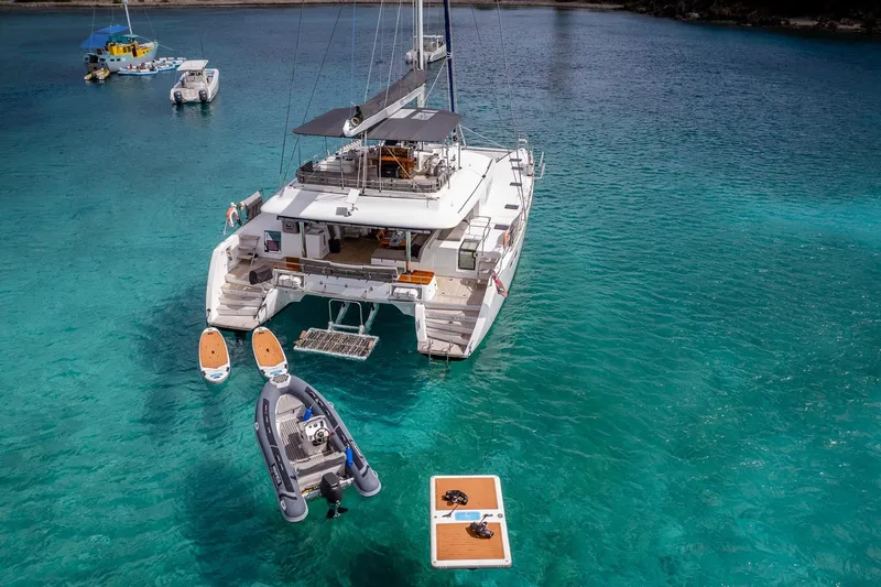 Bluewinds Yacht Photos Pics 2014 Lagoon 560 S2 catamaran anchored in clear turquoise waters with paddleboards and dinghy.