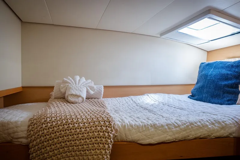 Bluewinds Yacht Photos Pics Cozy cabin interior of 2023 Lagoon 560 S2 yacht with plush bedding and skylight.