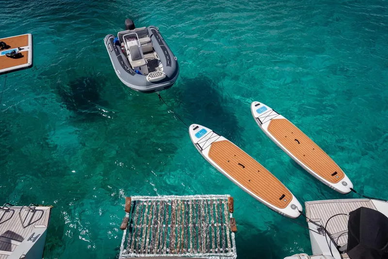 Bluewinds Yacht Photos Pics Aerial view of Lagoon 560 S2 yacht with paddleboards and dinghy in clear blue water.