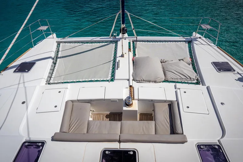 Bluewinds Yacht Photos Pics Luxurious Lagoon 560 S2 catamaran deck with seating and netting, 2023 model, on turquoise water.