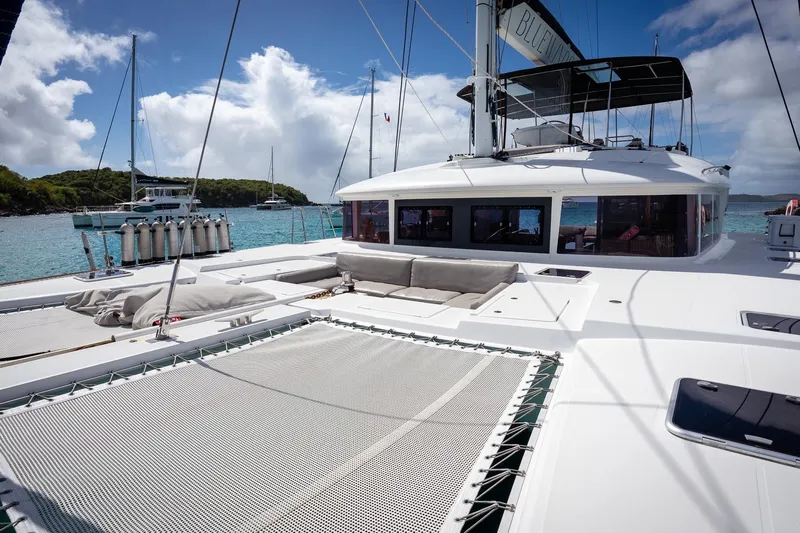 Bluewinds Yacht Photos Pics 2023 Lagoon 560 S2 catamaran with spacious deck, anchored in a scenic bay.
