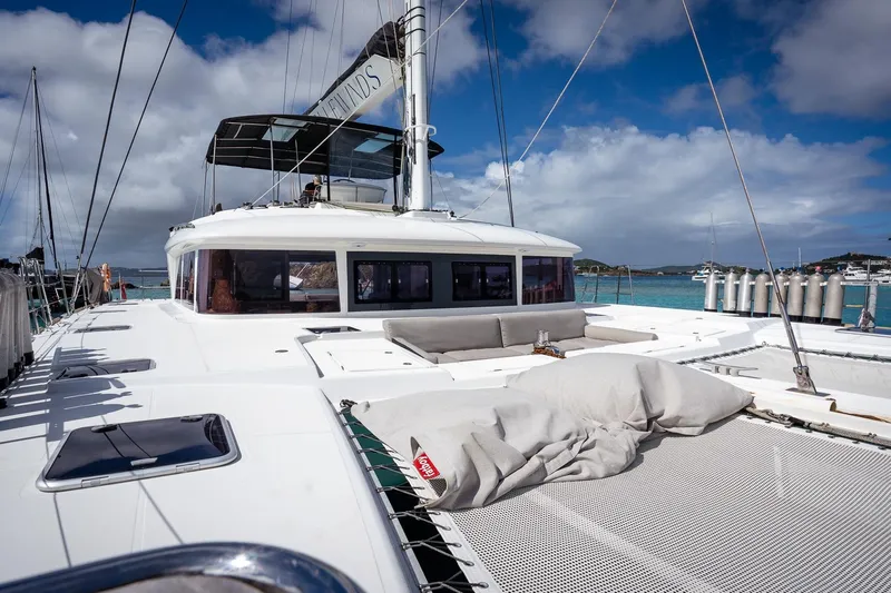Bluewinds Yacht Photos Pics 2023 Lagoon 560 S2 catamaran docked in a sunny marina with clear skies.