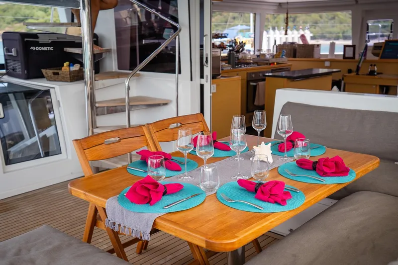 Bluewinds Yacht Photos Pics Elegant dining setup on Lagoon 560 S2 yacht, featuring vibrant tableware and cozy seating.